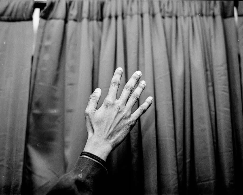 A hand pressed against a curtain